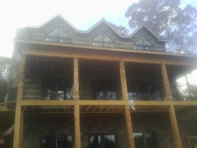 Dormers and porch framing on a large log home under construction — Roof Coating work by our crew in Edgemoor