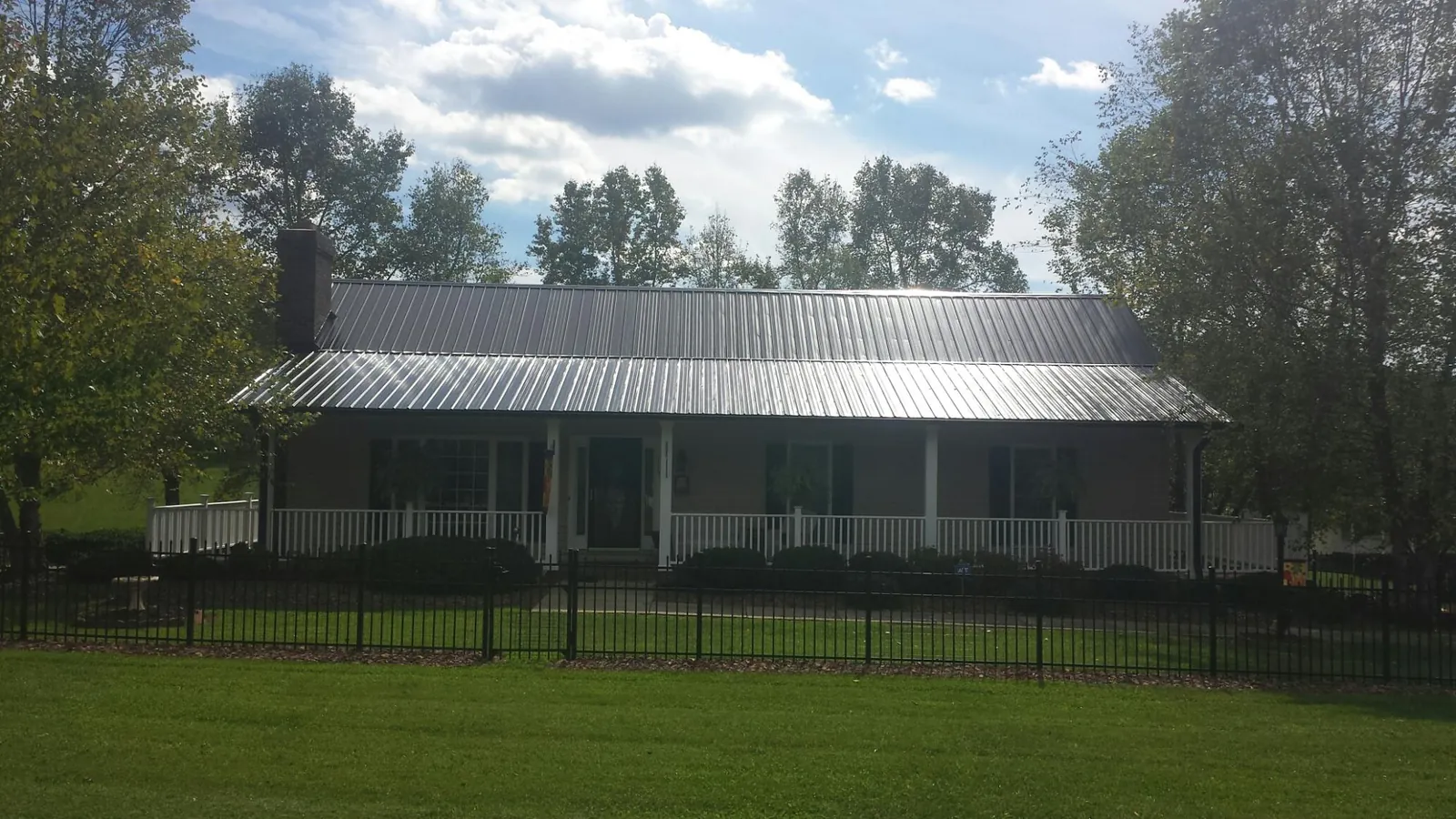 Gray metal roof on a brick ranch with a full width front porch — Gutter Guard Installation work by our crew in Edgemoor