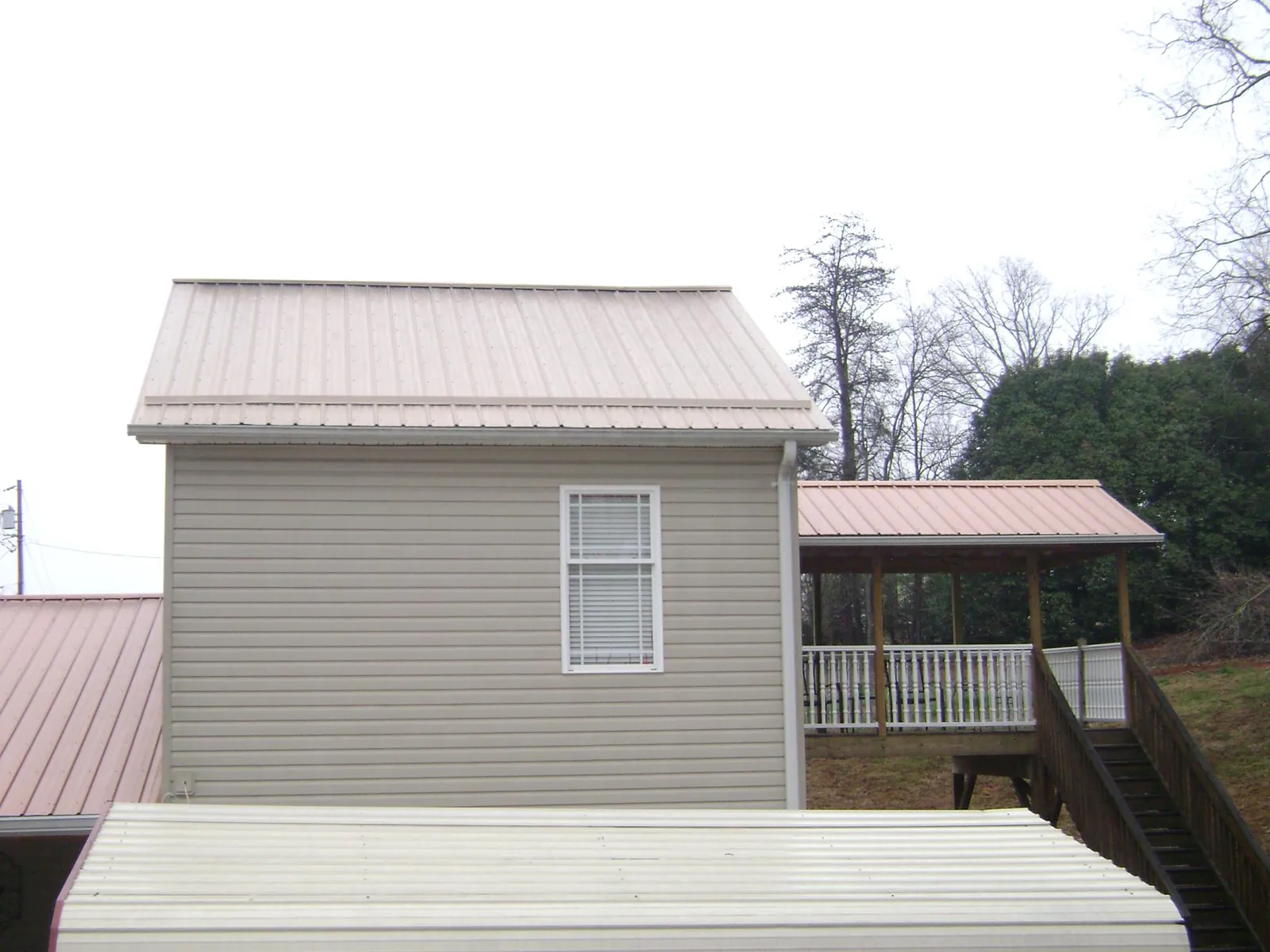 Tan metal roofs on a two story addition and attached porch, from a Roof Replacement job in Edgemoor