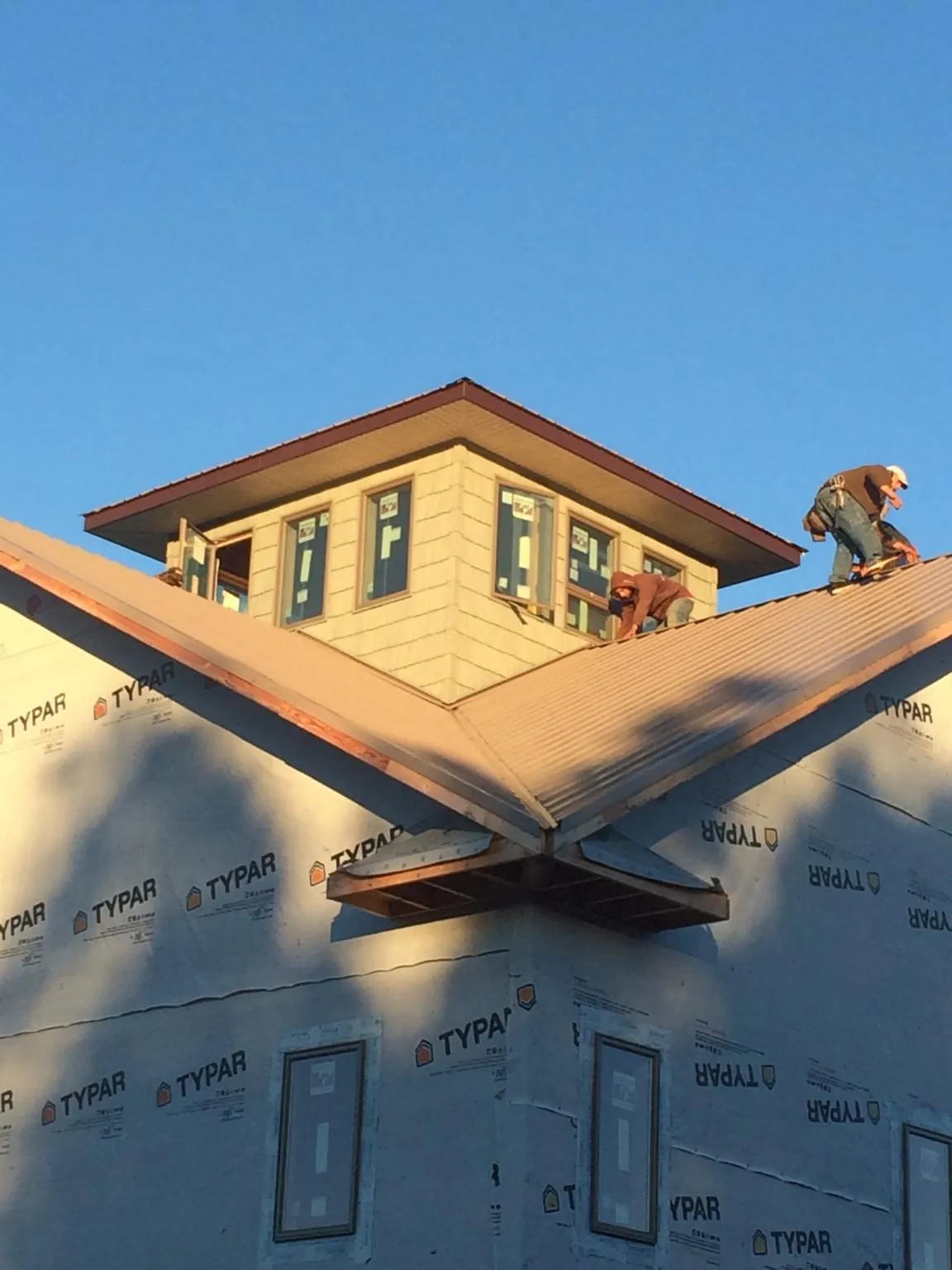 Roofers working around a rooftop cupola on a new metal roof at sunset — Roof Waterproofing in Edgemoor by Roofing Brothers